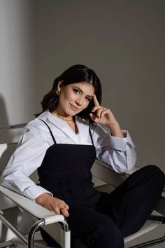 a woman sitting in a chair with her hand on her head and looking at the camera