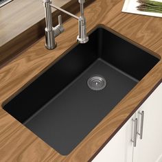 a black sink sitting on top of a wooden counter next to a faucet