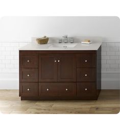 a bathroom vanity with white counter top and brown cabinetry, against a white brick wall