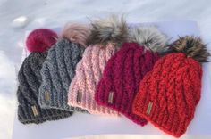 five different colored knitted hats with pom - poms