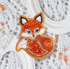 an orange fox brooch sitting on top of a white doily