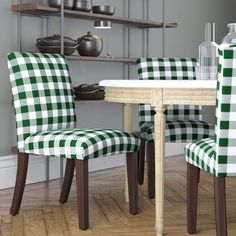 two green and white checkered chairs sitting in front of a wooden table with plates on it