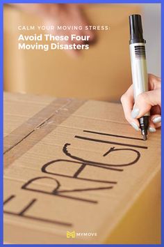 a person writing on a moving box with the words move written on it and a pen in their hand