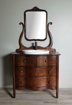 a wooden dresser with a mirror above it and a white sink in front of it