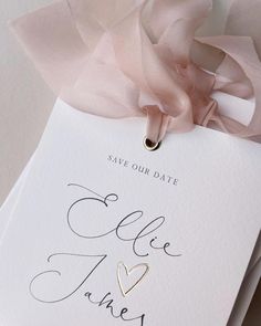 a close up of a white card with a pink ribbon on it and the words, save our date written in cursive writing