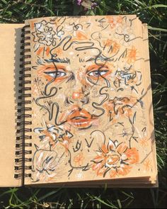 an open notebook with graffiti on it sitting in the grass