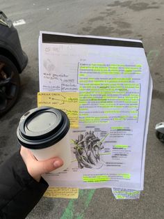 a person holding up a coffee cup next to a parking meter