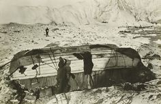 an old black and white photo shows people standing around a tent in the desert with mountains in the background