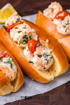 three hot dogs with shrimp and tomatoes on them