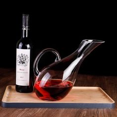 a bottle of wine sitting next to a glass pitcher on top of a wooden tray