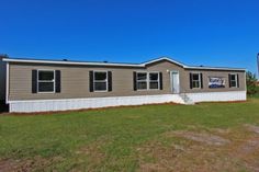 a mobile home sits in the middle of a grassy area with a blue sky behind it