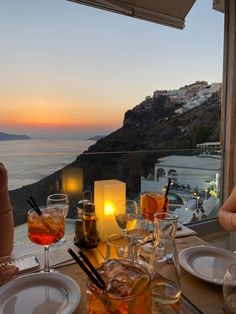 people are sitting at a table with drinks and beverages on it, overlooking the ocean