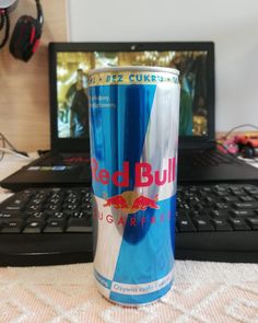 a can of red bull is sitting in front of a laptop