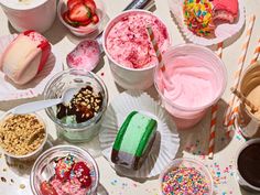 ice creams and desserts are arranged on a table with strawberries, cookies, and sprinkles