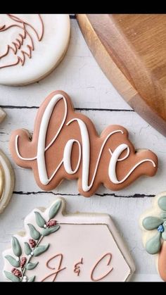 decorated cookies with the word love spelled in cursive writing on them next to other cookie decorating supplies