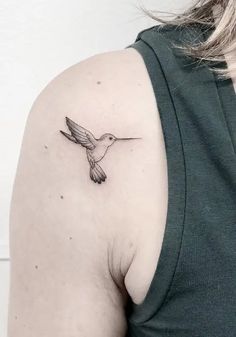 a small hummingbird tattoo on the back of a woman's left upper arm