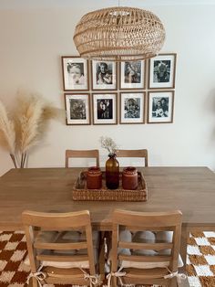 a dining room table with chairs and pictures on the wall