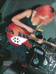 a woman with red hair playing an electric guitar