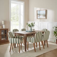 a dining room table with striped chairs and a potted plant on top of it