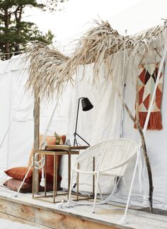 a table and chair in front of a white tent with grass on the outside wall