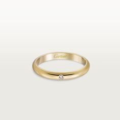 a yellow gold ring with a single diamond on the top, and an inscription that says cartier