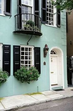 a blue building with black shutters and flowers in the window boxes on the side