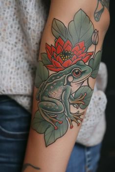 a woman with a tattoo on her arm holding onto a flower and frog sitting on top of it