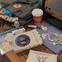 an assortment of items on a table including books, notebooks and a bag