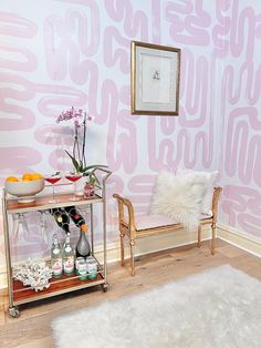 a living room with pink wallpaper and white fur rugs on the wooden floor