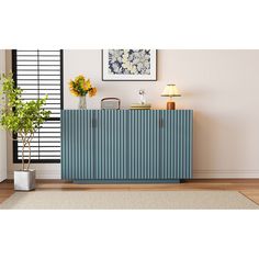 a blue cabinet sitting on top of a hard wood floor next to a potted plant