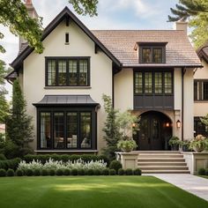 a large white house with black trim on the front and side doors, windows, and stairs