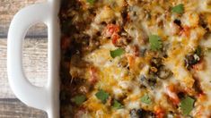 a casserole dish with meat, cheese and vegetables in it on a wooden table