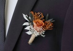 a boutonniere with an orange rose and baby's breath