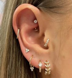 a woman wearing three different types of ear piercings