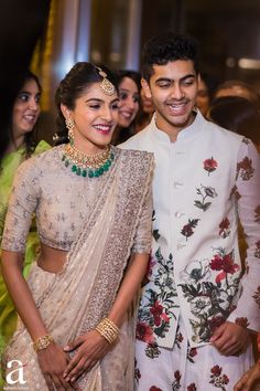 a man and woman standing next to each other in front of people wearing white outfits