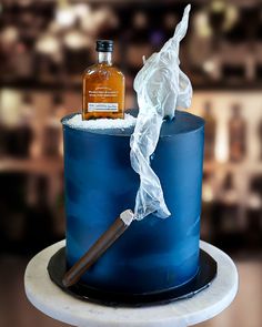 a blue cake with a bottle of whiskey on top and tissue wrapped around the edge