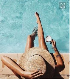 a woman laying on the side of a swimming pool with her feet up in the air