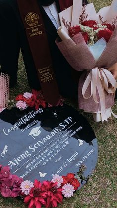 a man kneeling down next to a plaque with flowers on it and a bunch of books