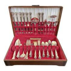 an old wooden box filled with silverware and utensils in red velvet cases