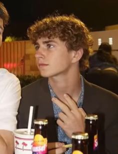 two young men sitting at a table with drinks and sodas in front of them