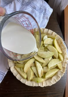 a person pouring milk into a bowl filled with apples