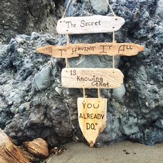 a wooden sign hanging from the side of a rock