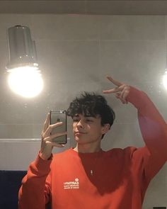 a young man taking a selfie in front of a mirror with his cell phone