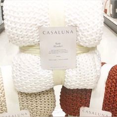 several knitted blankets are stacked on top of each other in a store display case