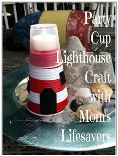 a red and white lighthouse candle sitting on top of a glass plate