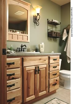 a bathroom with green walls and wooden cabinets