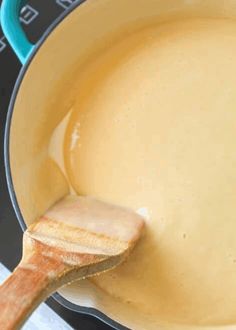 a wooden spoon in a yellow sauce on top of an oven burner with the lid down