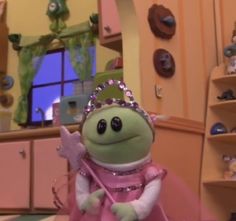 the frog is dressed in pink and has a tiara on her head while holding a wand