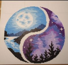 a cross - stitch picture of the yin symbol with mountains and trees in the background