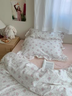 an unmade bed with pink and white flowers on it